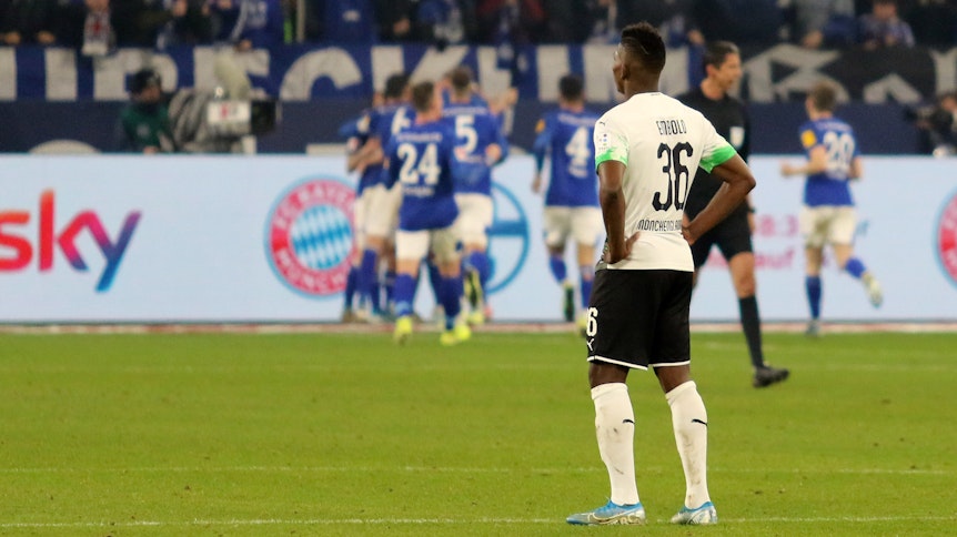 Breel Embolo steht enttäuscht auf dem Rasen, während seine Schalker Ex-Kollegen jubeln.