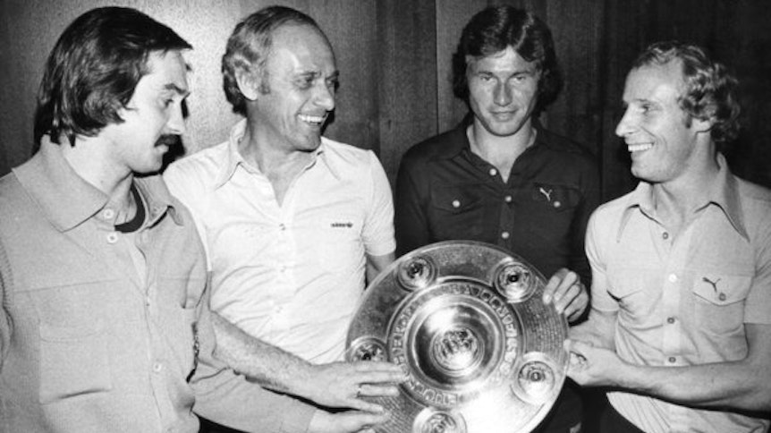 Fohlend-Held Jupp Heynckes (2.v.r.) präsentiert gemeinsam mit Trainer Udo Lattek (2.v.l.), sowie den Team-Kollegen Uli Stielike (l.) und Berti Vogts (r.) im Mai 1977 nach einem 2:2 bei den Bayern in einem Münchner Hotel die Meisterschale.