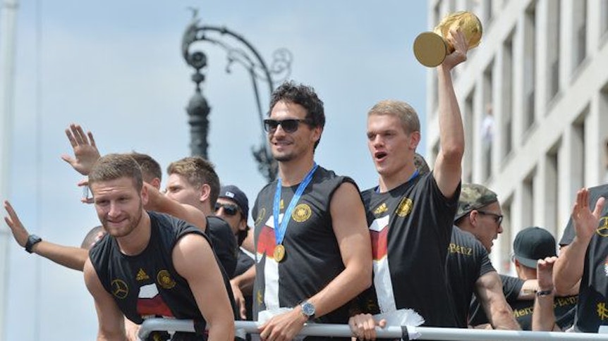 Matthias Ginter (r.) zeigt neben Mats Hummels (m.) und Shkodran Mustafi (l.) 2014 den WM-Pokal beim Triumphzug durch Berlin.