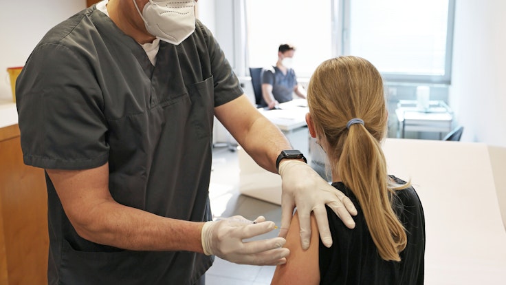 Ein zwölfjähriges Mädchen wird in einer Arztpraxis von dem Hausarzt Tim Koop (l) mit dem Serum von Biontech/Pfizer geimpft.