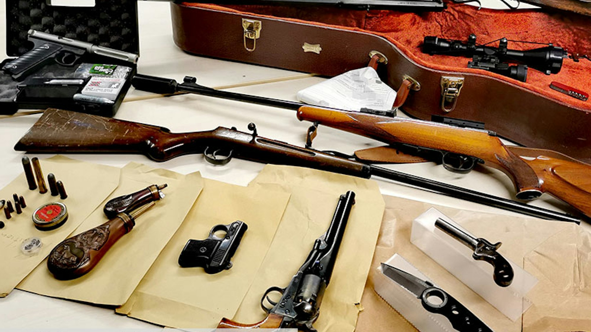 Auf einem Tisch liegen sichergestellte Gewehre, Pistolen, Messer und Munition.