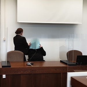 Vor dem Kölner Landgericht hält sich der Angeklagte eine Akte vor sein Gesicht.