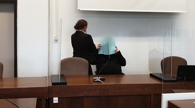 Vor dem Kölner Landgericht hält sich der Angeklagte eine Akte vor sein Gesicht.