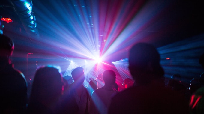 Menschen feiern in dem Symbolbild in einer Disco, Silhouetten sind im Laser-Licht zu sehen. Eine Reiserückkehrerin aus Mallorca sorgte in einem Club in Karlsruhe für einen Corona-Ausbruch.