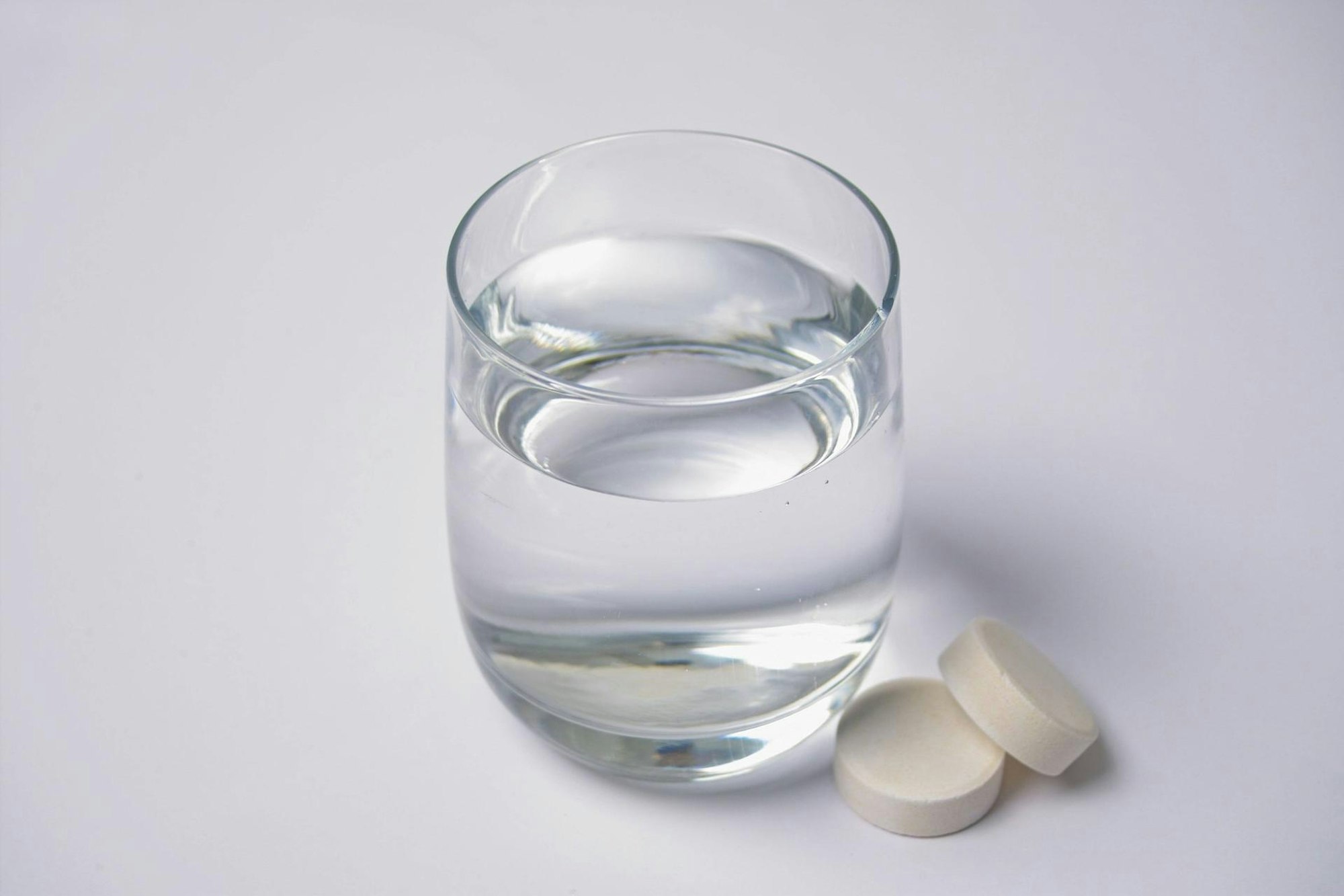 Das Symbolbild zeigt ein Wasserglas mit zwei Tabletten, die daneben liegen.Der Hersteller Abtei ruft bestimmte Vitamin-Präparate zurück, die bundesweit verkauft wurden.