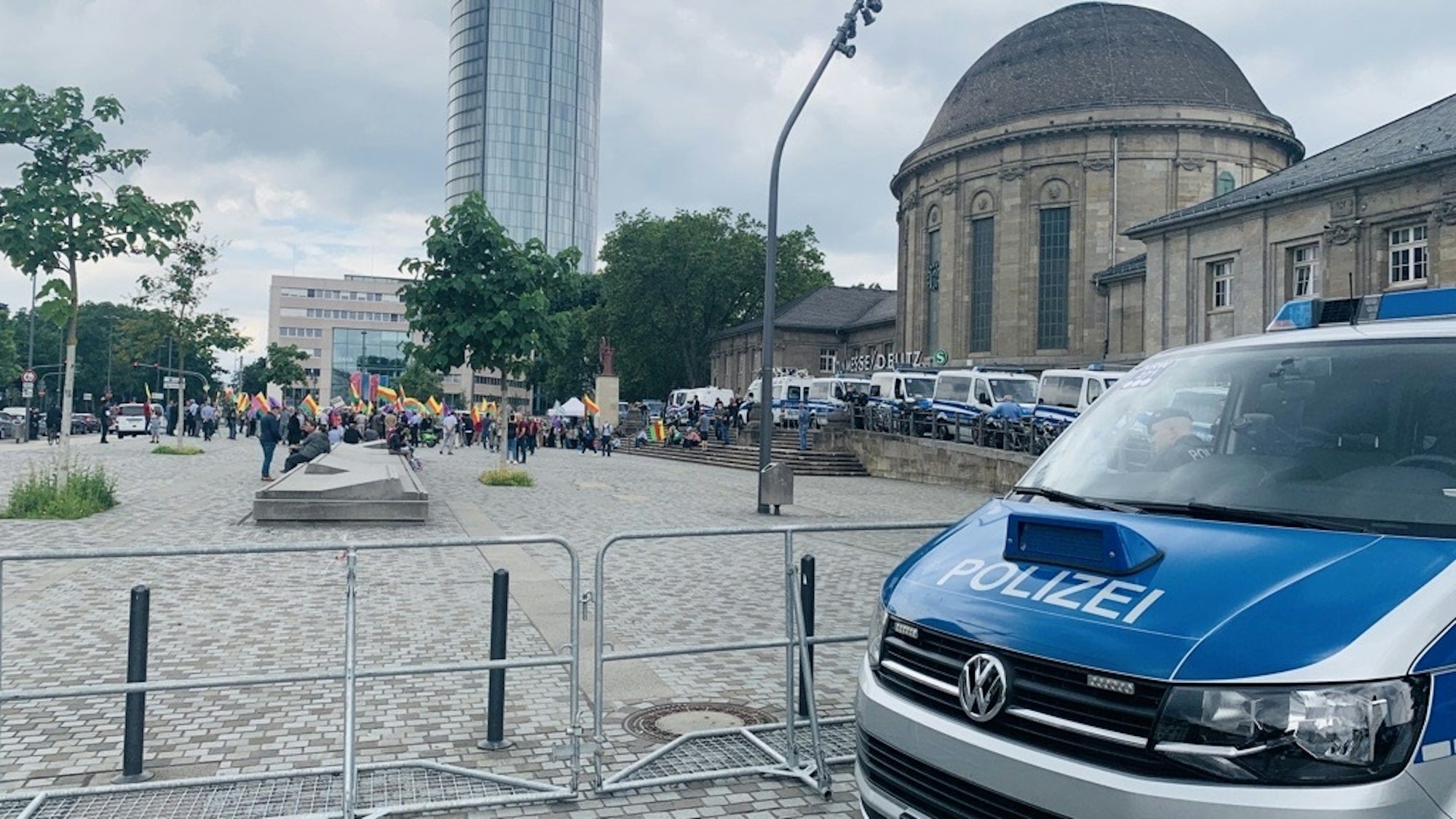 Ein Wagen der Kölner Polizei steht vor dem Deutzer Bahnhof. Im Hintergrund sind Demonstrierende zu sehen.