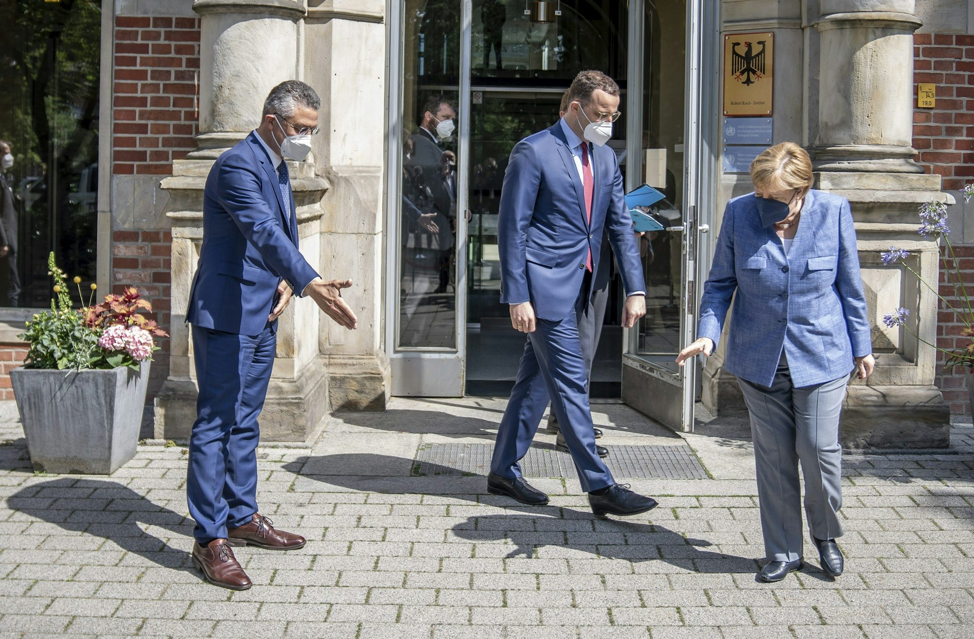 Kanzlerin Angela Merkel, Gesundheitsminister Spahn und RKI-Chef Lothar Wieler stehen vor dem Eingang des Robert Koch-Instituts.