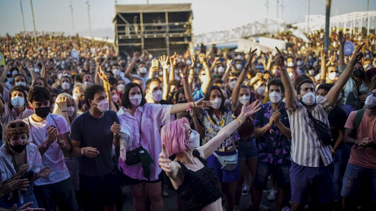Menschen mit Mund-Nasen-Schutz besuchen das Cruilla Musikfestival in Barcelona und feiern.