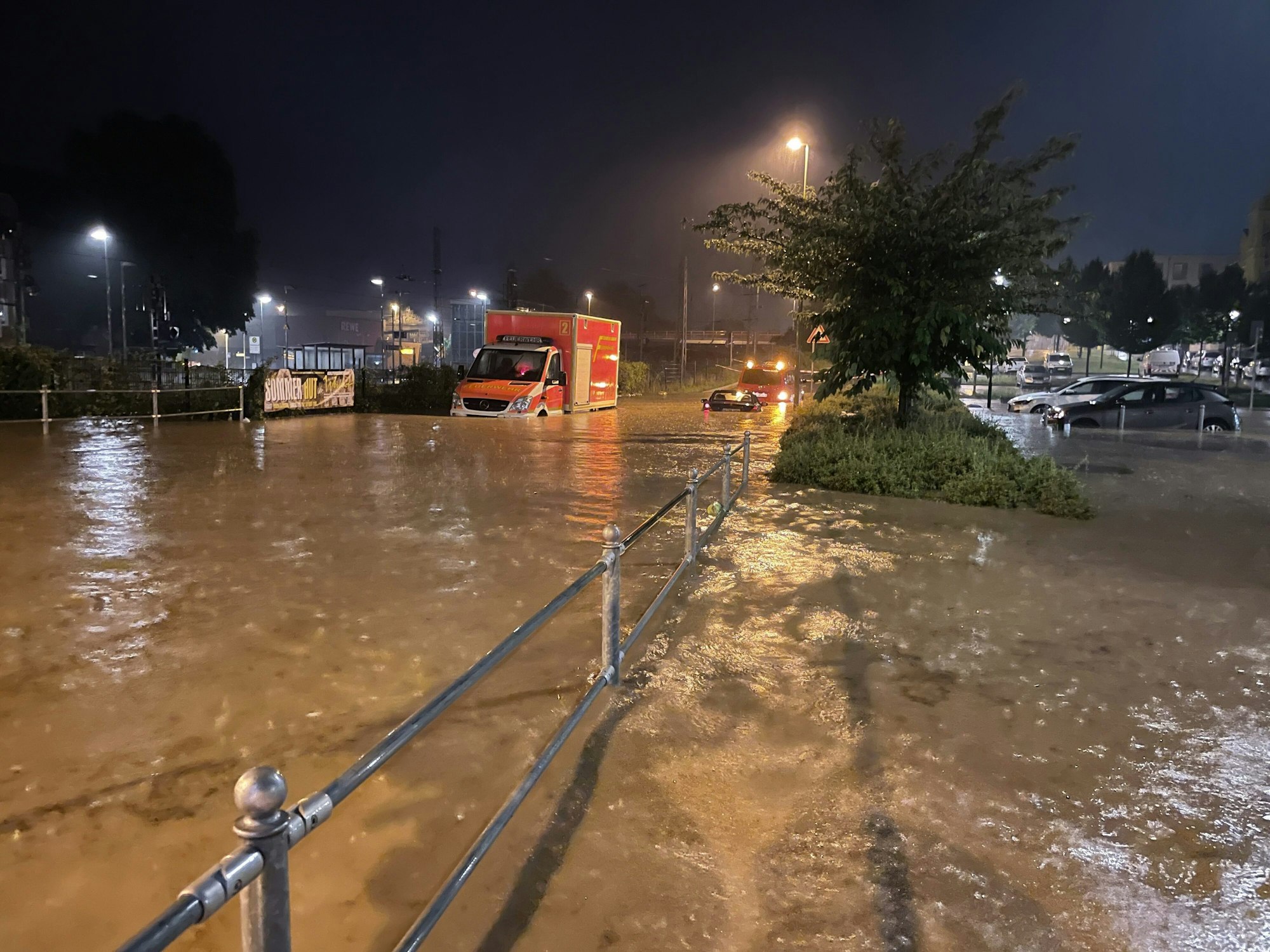 Autos und ein Rettungswagen sind auf einer überfluteten Straße zu sehen.