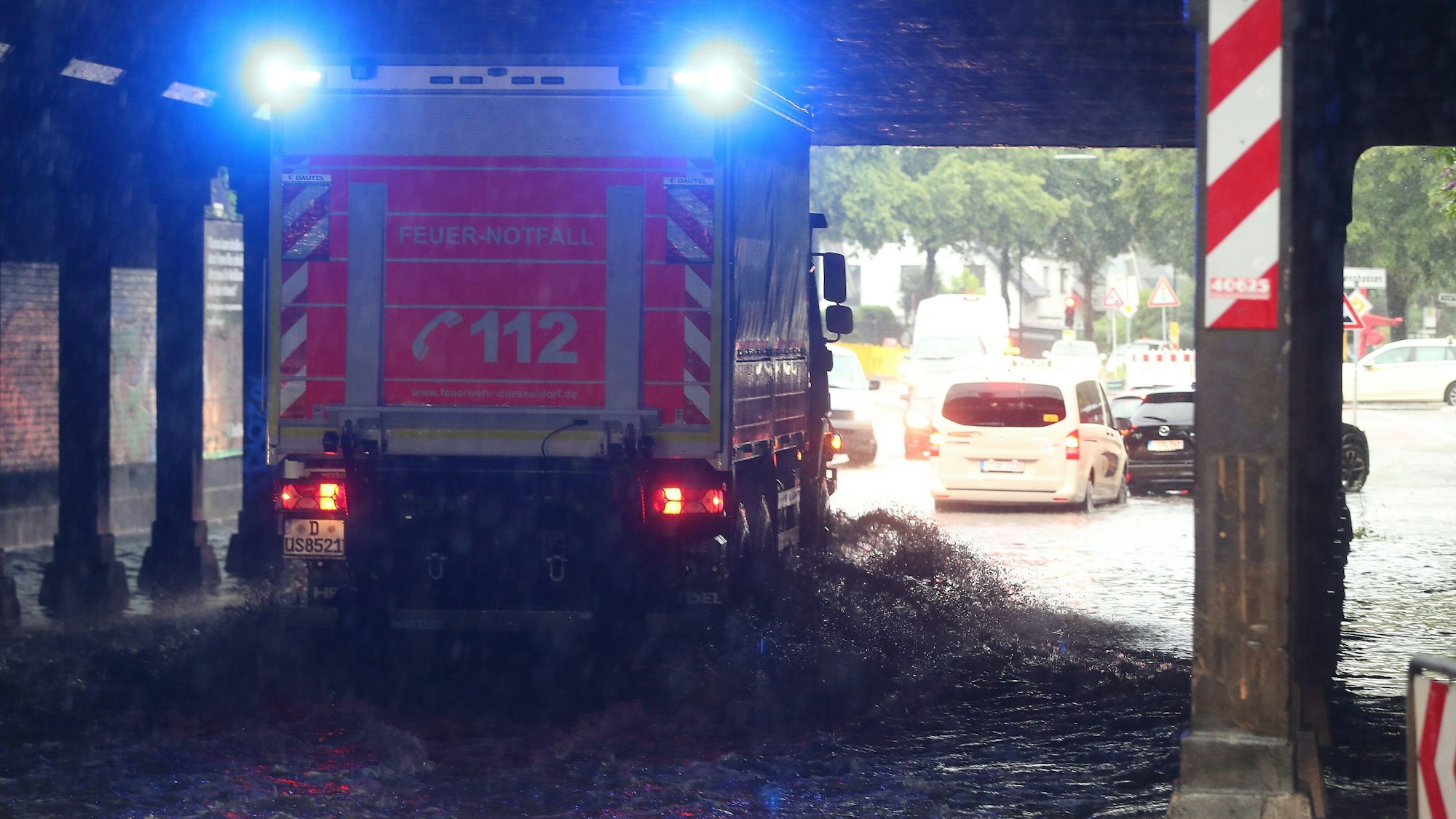 Ein Feuerwehr-Fahrzeug fährt durch eine durchflutete Überführung.