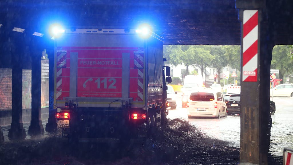 Ein Feuerwehr-Fahrzeug fährt durch eine durchflutete Überführung.