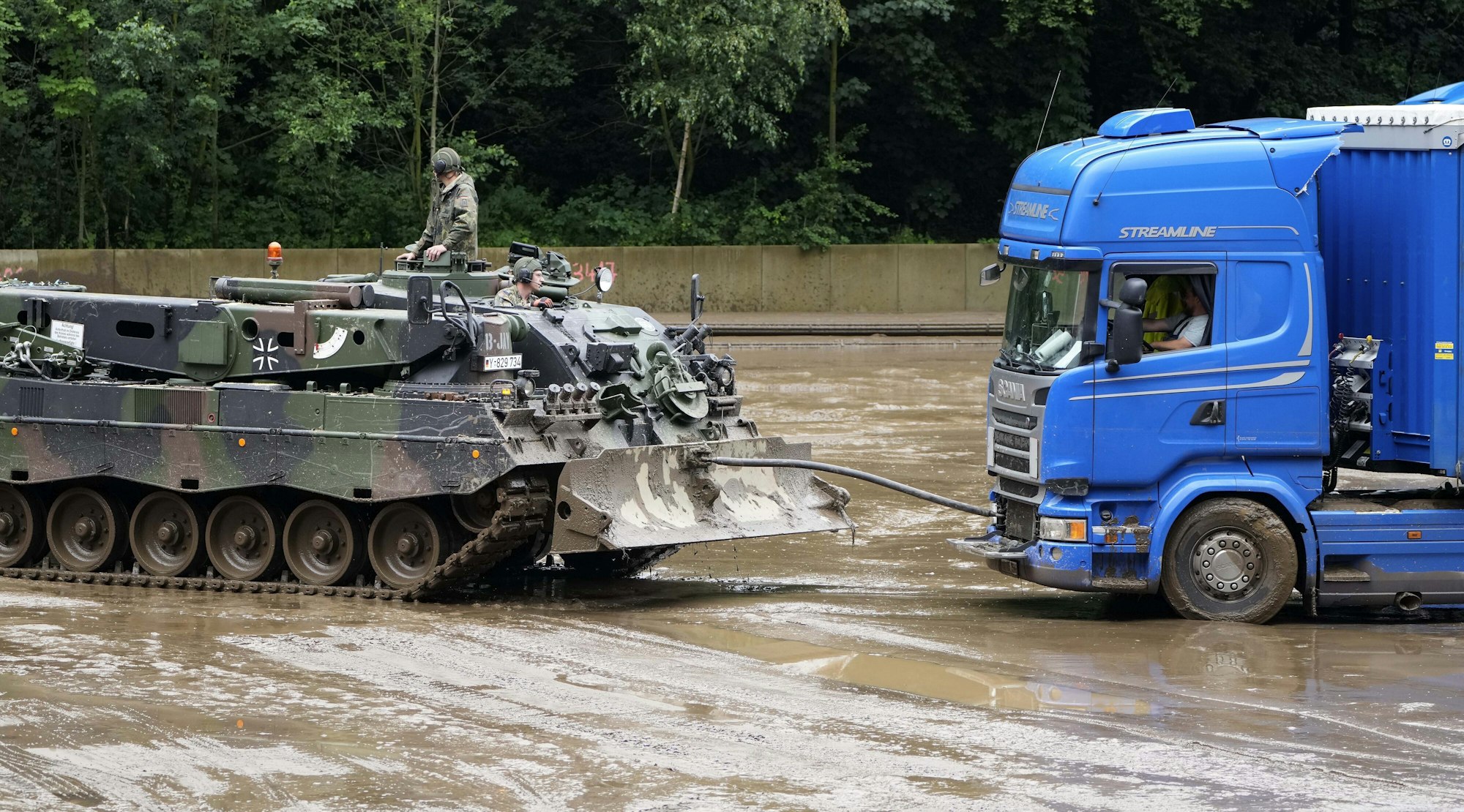 Ein Panzer der Bundeswehr zieht am Donnerstag (15. Juli) einen Lkw in Hagen aus dem Schlamm, nachdem es dort zu Überschwemmungen kam. Die Bundeswehr unterstützt die Hilfs- und Aufräumarbeiten in der Region.