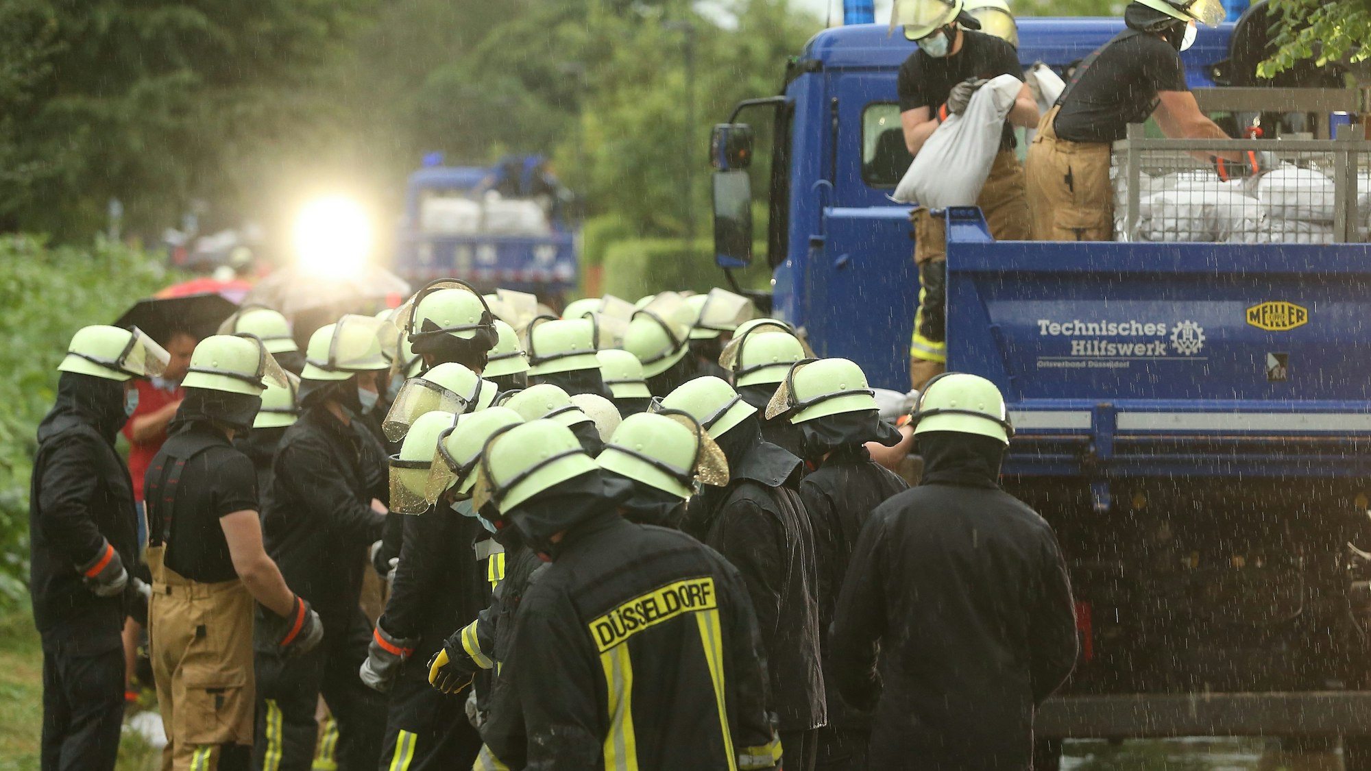 14.07.2021, Nordrhein-Westfalen, Düsseldorf: Feuerwehrleute arbeiten in der Ostparksiedlung. Die Feuerwehr versucht, die Wassermassen mit Sandsäcke zu stoppen. Foto: David Young/dpa +++ dpa-Bildfunk +++