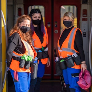 Drei Reinigungskräfte der mobilen Reinigung der S-Bahn München stehen in der Tür einer stehenden S-Bahn und sorgen dafür, dass während der Corona-Zeit Kontaktflächen richtig desinfiziert sind.