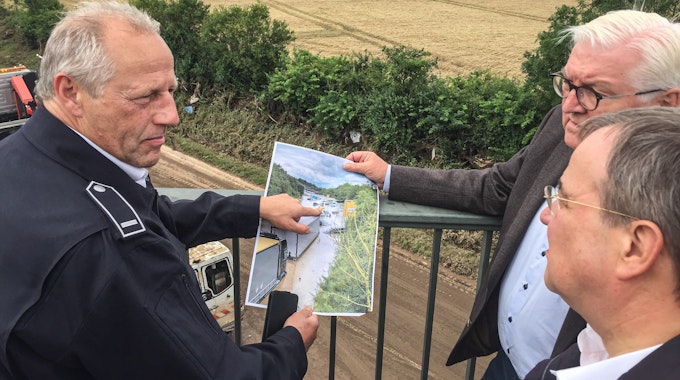 Feuerwehrmann Udo Milewski (links) erklärt NRW-Ministerpräsident Armin Laschet (vorne) und Bundespräsident Frank-Walter Steinmeier an der B265 im Ortsteil Liblar die Situation nach der Flutkatastrophe.