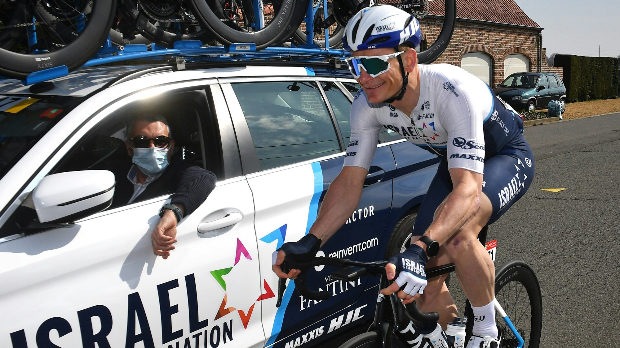 André Greipel fährt neben dem Teamwagen vom Team Israel Start-Up Nation auf seinem Rad.