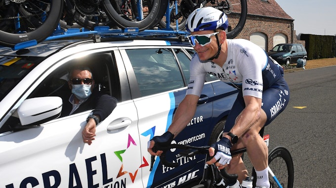 André Greipel fährt neben dem Teamwagen vom Team Israel Start-Up Nation auf seinem Rad.