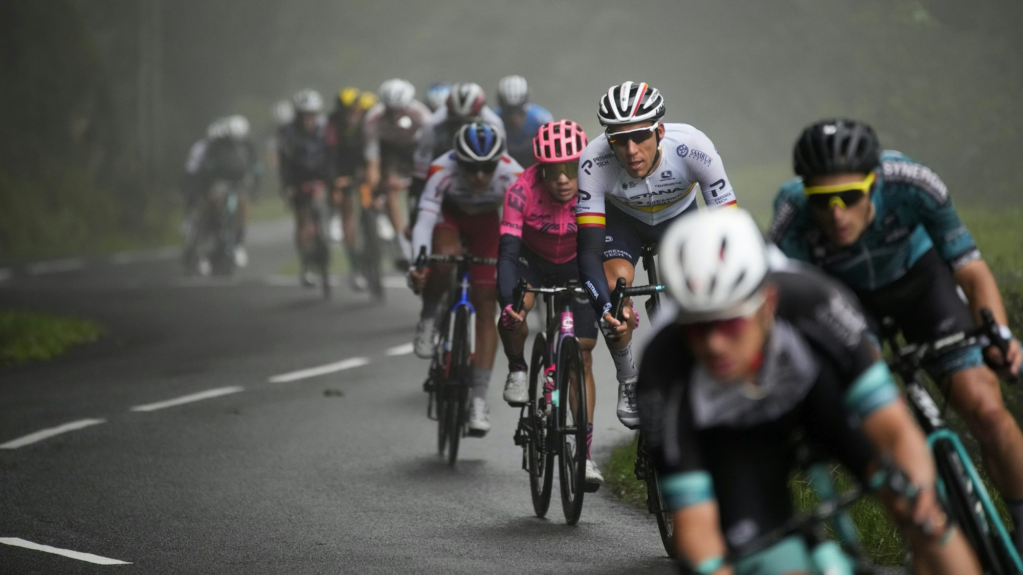 Bei der Tour de France fährt das Peloton im Nebel eine Bergabfahrt hinunter.