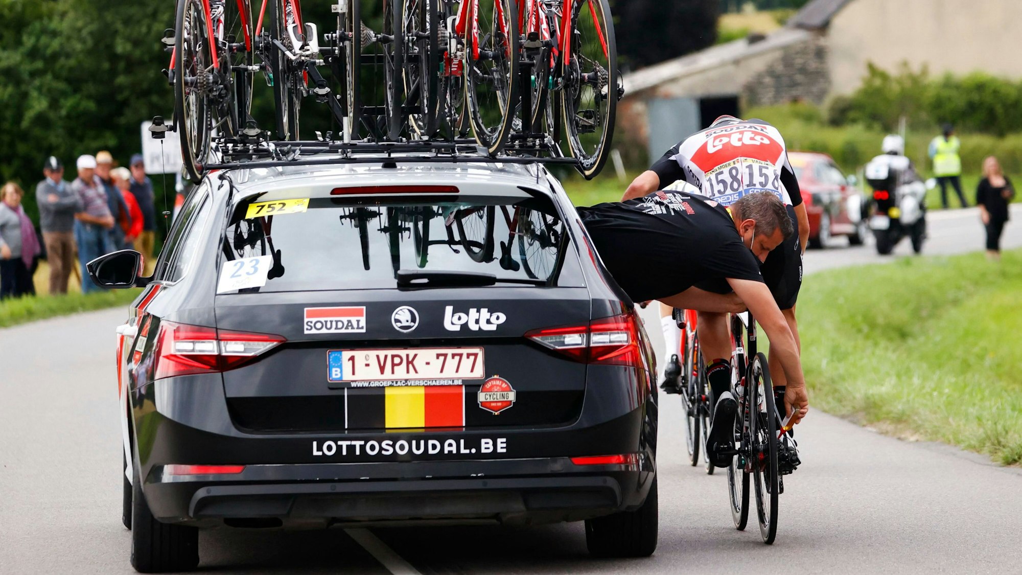 Das Rennrad von Brent Van Moer wird bei der Tour de France aus dem Auto heraus repariert, während der Belgier auf dem Rad sitzt.