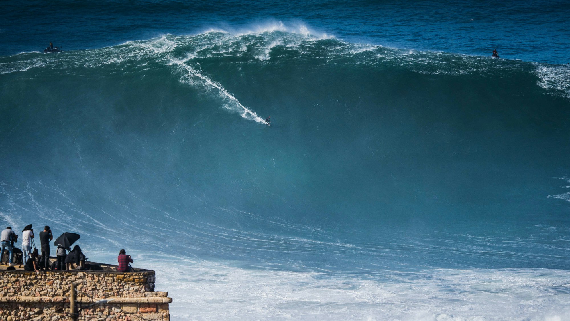 Ein Surfer reitet in Portugal auf einer riesigen Welle im Atlantik.