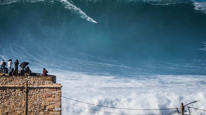 Ein Surfer reitet in Portugal auf einer riesigen Welle im Atlantik.