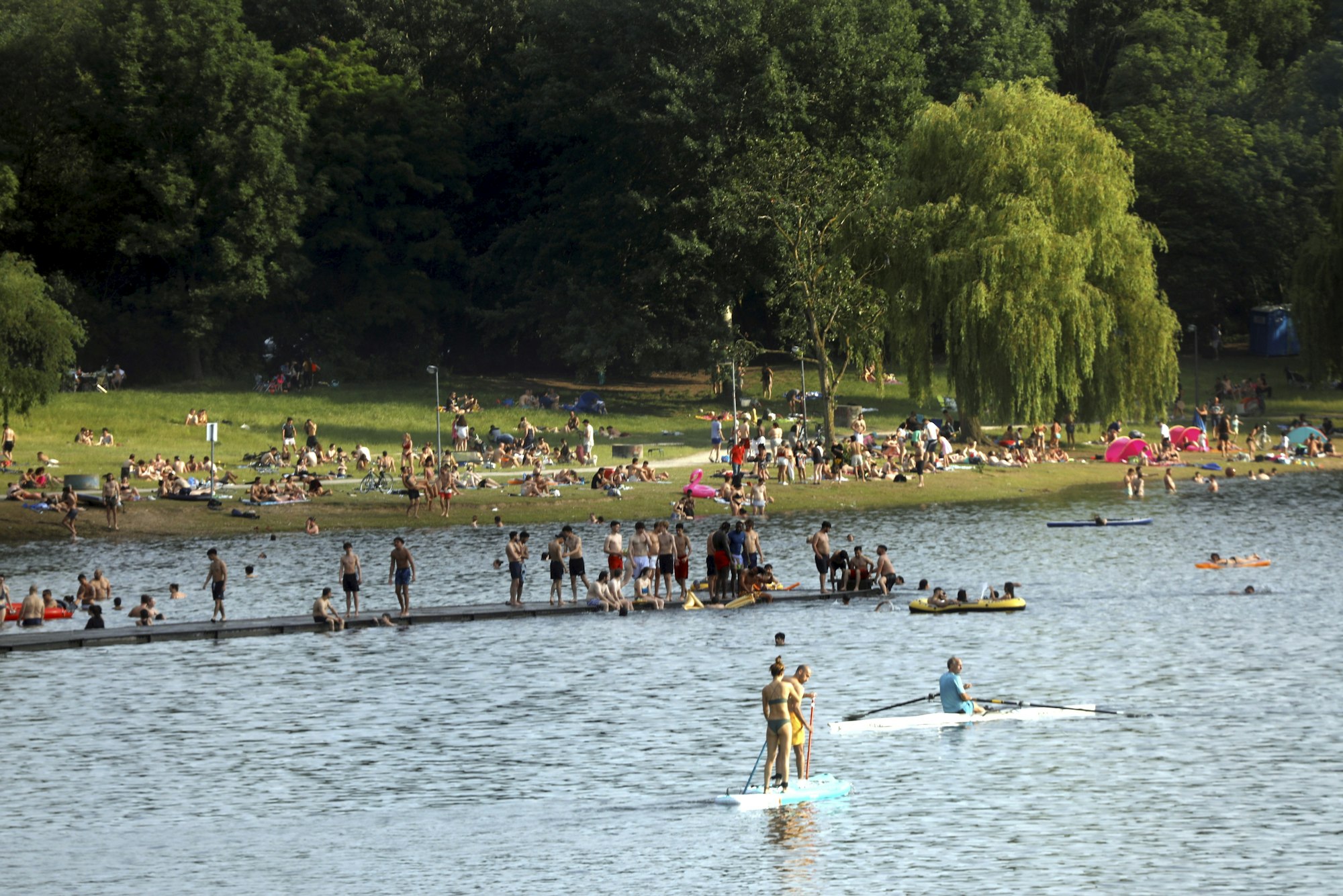 Menschen baden bei Sonnenschein am Fühlinger See in Köln.