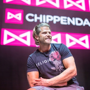 Paul Janke gibt es jetzt auf Onlyfans. Hier sitzt er in München vor dem Logo der Strippercombo Chippendales.