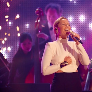 Helene Fischer singt beim RTL-Jahresrückblick mit Mikrofon in der Hand und ihrer Band im Hintergrund.