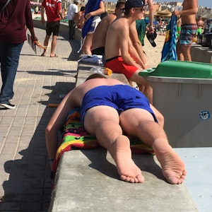 Ein Mann liegt am 30.06.2016 in Palma de Mallocra (Spanien) am Playa de Palma neben einer umgekoippten Bierdose und einem Abfalleimer auf einer Mauer. Symbolbild für einen Mann, der am Ballermann auf Mallorca totgeprügelt worden ist