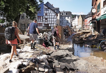 Helfer gehen durch den Ortskern. In Bad Münstereifel hat die über die Ufer getretene Erft erhebliche Schäden angerichtet.