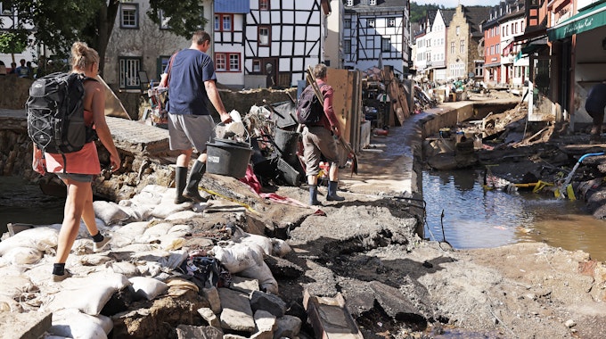 Helfer gehen durch den Ortskern. In Bad Münstereifel hat die über die Ufer getretene Erft erhebliche Schäden angerichtet.&nbsp;