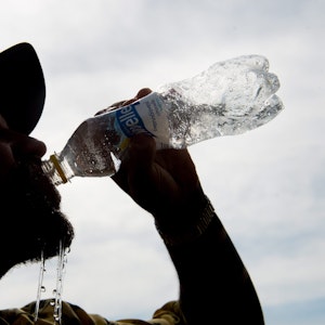 Auf unseren Symbolfoto ist ein Mann mit Mütze zu sehen, der aus einer Flasche Wasser trinkt.