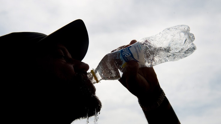 Auf unseren Symbolfoto ist ein Mann mit Mütze zu sehen, der aus einer Flasche Wasser trinkt.