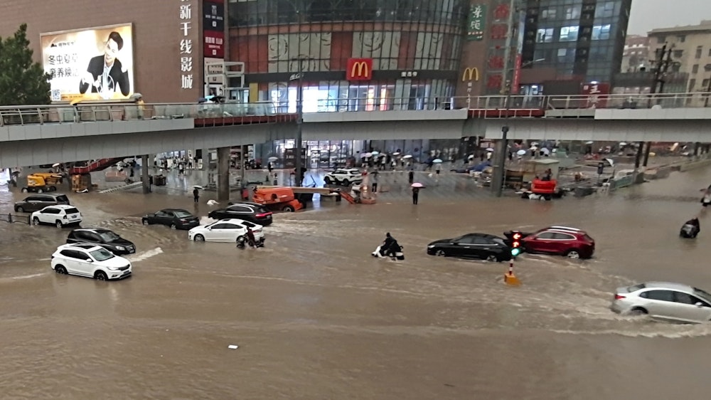 Fahrzeuge stehen in der zentralchinesischen Provinz Henan auf einer überfluteten Straße.