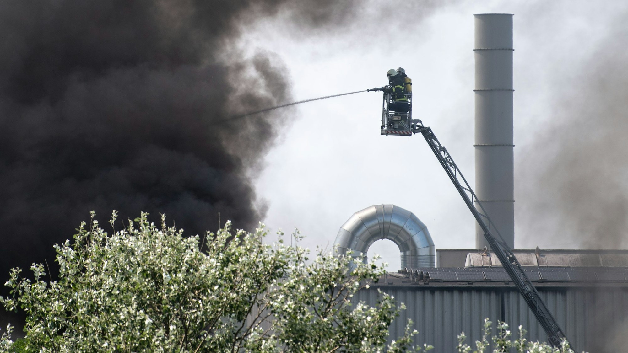 Erftstadt: Feuerwehrleute bekämpfen von einer Drehleiter aus einen Brand in einer Lagerhalle.