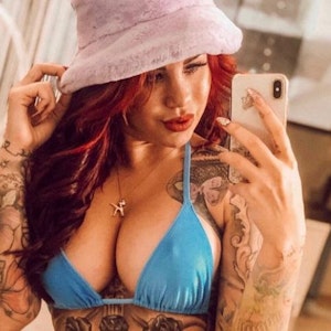 Kate Merlan posiert in einem blauen Bikini mit einem Handy vor dem Spiegel.
