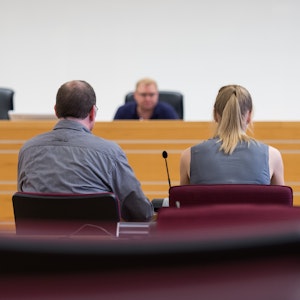 Ein Mann und eine Frau sitzen in einem Gerichtssaal vorm Richter.