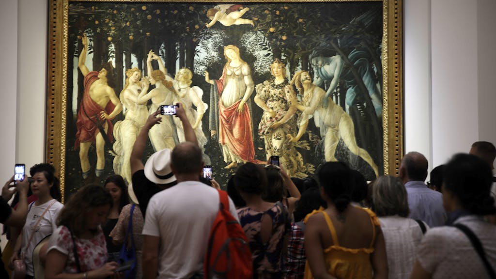 Mehrere Museumsbesucher stehen vor einem großen Kunstwerk, dem „Frühling” von Sandro Botticelli.
