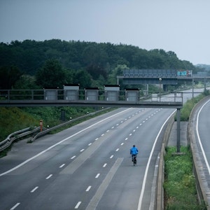 Ein Fahrradfahrer fährt über die gesperrte Autobahn A1 nahe Blessem in Erftstadt.
