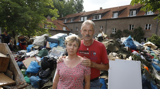 Iris und Rolf Friebel stehen in Hahn vor einem Müllberg aus Dingen, die beim Hochwasser zerstört wurden.