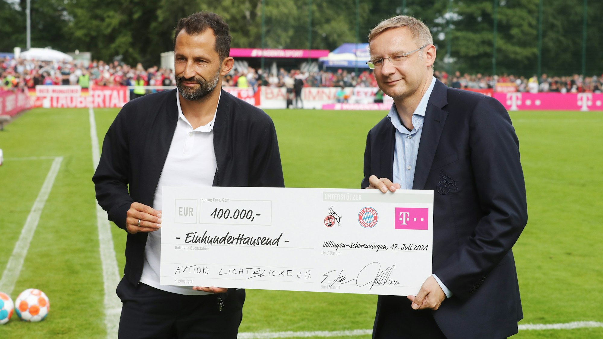 Eckhard Sauren und Bayerns Sportvorstand Hasan Salihamidzic übergeben einen Scheck.