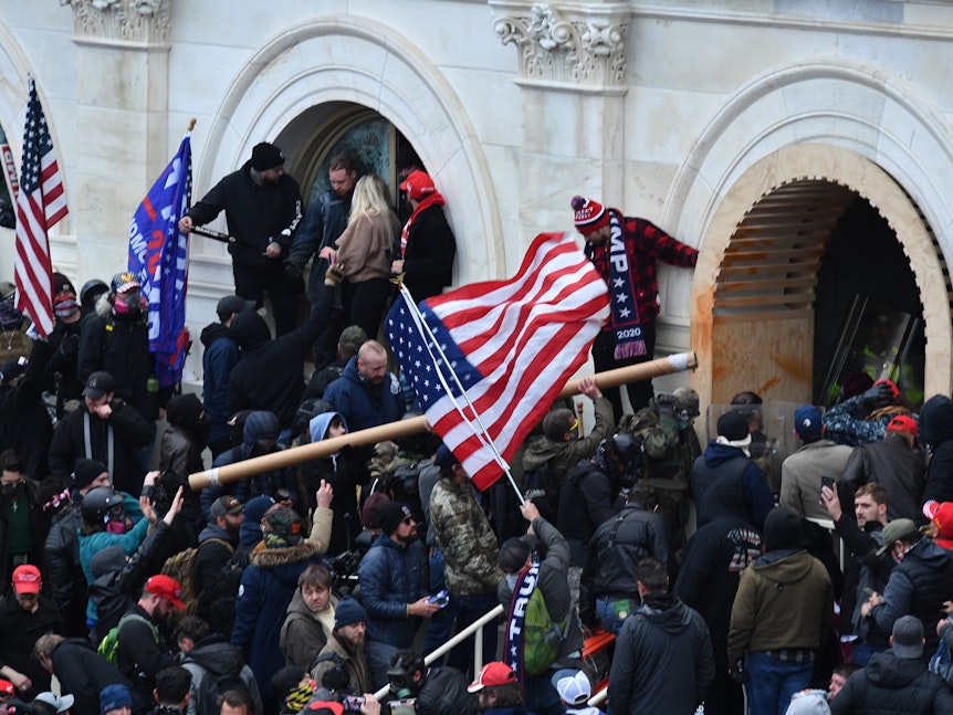 Anhänger des damaligen US-Präsidenten Trump stürmen das US-Kapitolgebäude mit USA-Flaggen.