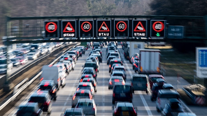 Dichter Verkehr schiebt sich über die Autobahn 8 in Fahrtrichtung Salzburg und Brenner-Autobahn im Hofoldinger Forst, während über der Straße auf einer digitalen Anzeige vor Stau gewarnt wird.