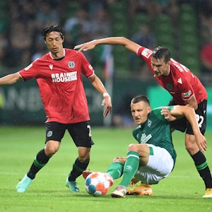 Werder Bremens Maximilian Eggestein im Duell mit Sei Muroya und Sebastian Stolze von Hannover 96