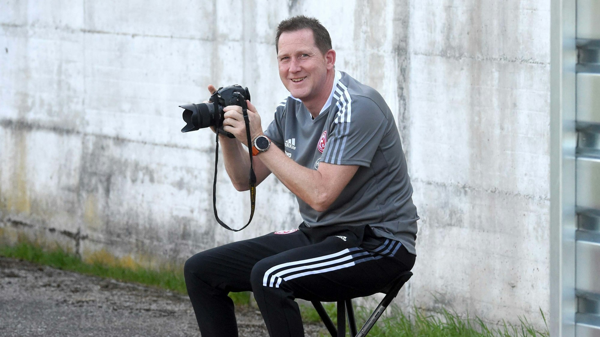 Uwe Klein posiert mit einem Fotoapparat in den Händen.