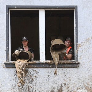 Unmittelbar nach der Flut kippen Helfer Schlamm aus Eimern in einem Haus in Dernau (Ahrtal)