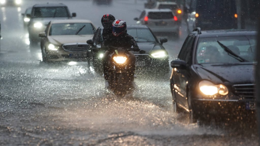 Autos und Motorräder fahren bei starkem Regen am 25.07.2021 über die überflutete Friedrichstraße in Berlin-Mitte.