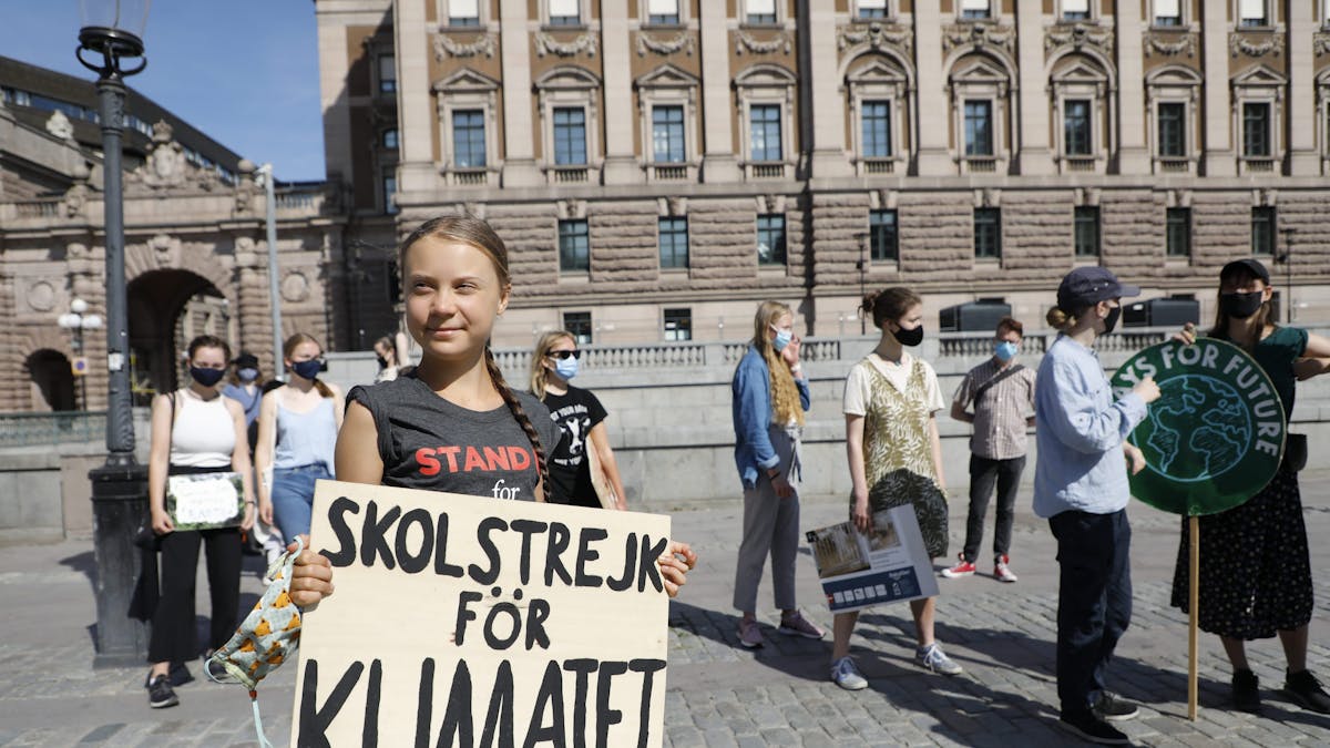 Greta Thunberg ist geimpft und hält ihr Schild mit der Aufschrift „Skolstrejk för Klimatet” in den Händen.
