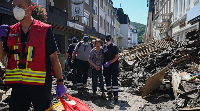 Helfer der Johanniter in Bad Neuenahr-Ahrweiler begleiten nach der Flutkatastrophe eine Seniorin aus ihrer Wohnung.