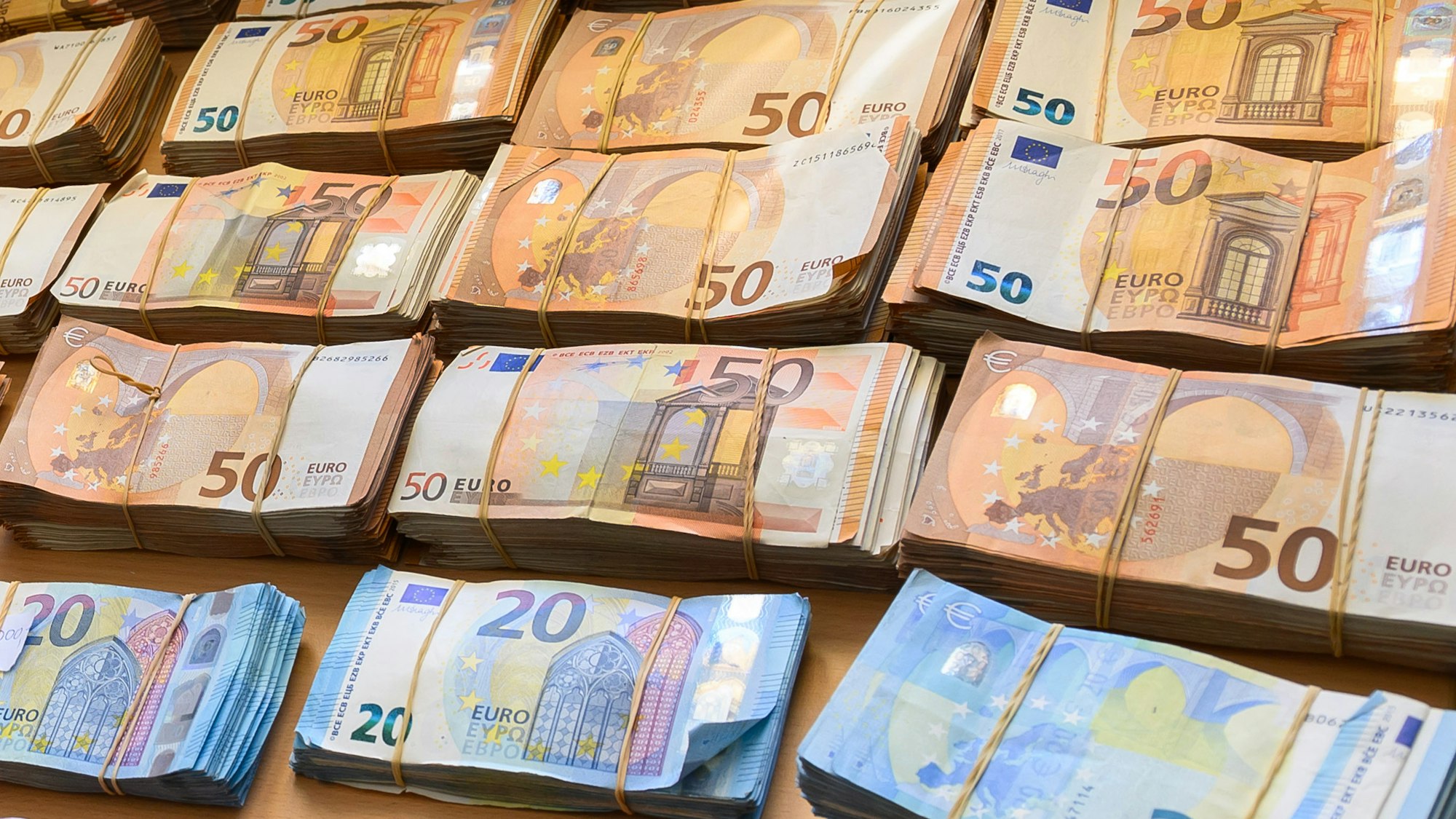 Auf einem Tisch liegen Bündel aus Fünfzig- und Zwanzig-Euro-Scheinen.